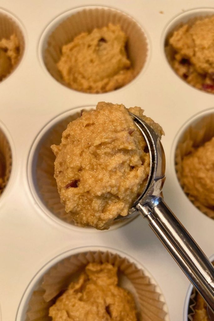 medium cookie scoop used to transfer cranberry pumpkin muffin batter to muffin pan