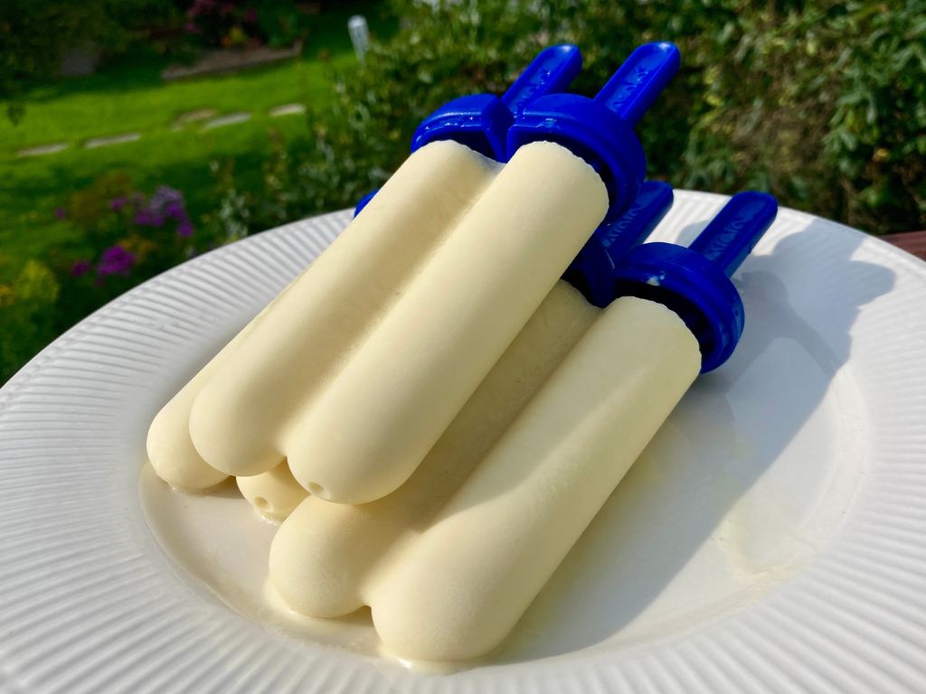 stack of orange creamsicle popsicles on a white plate, outside in the summer