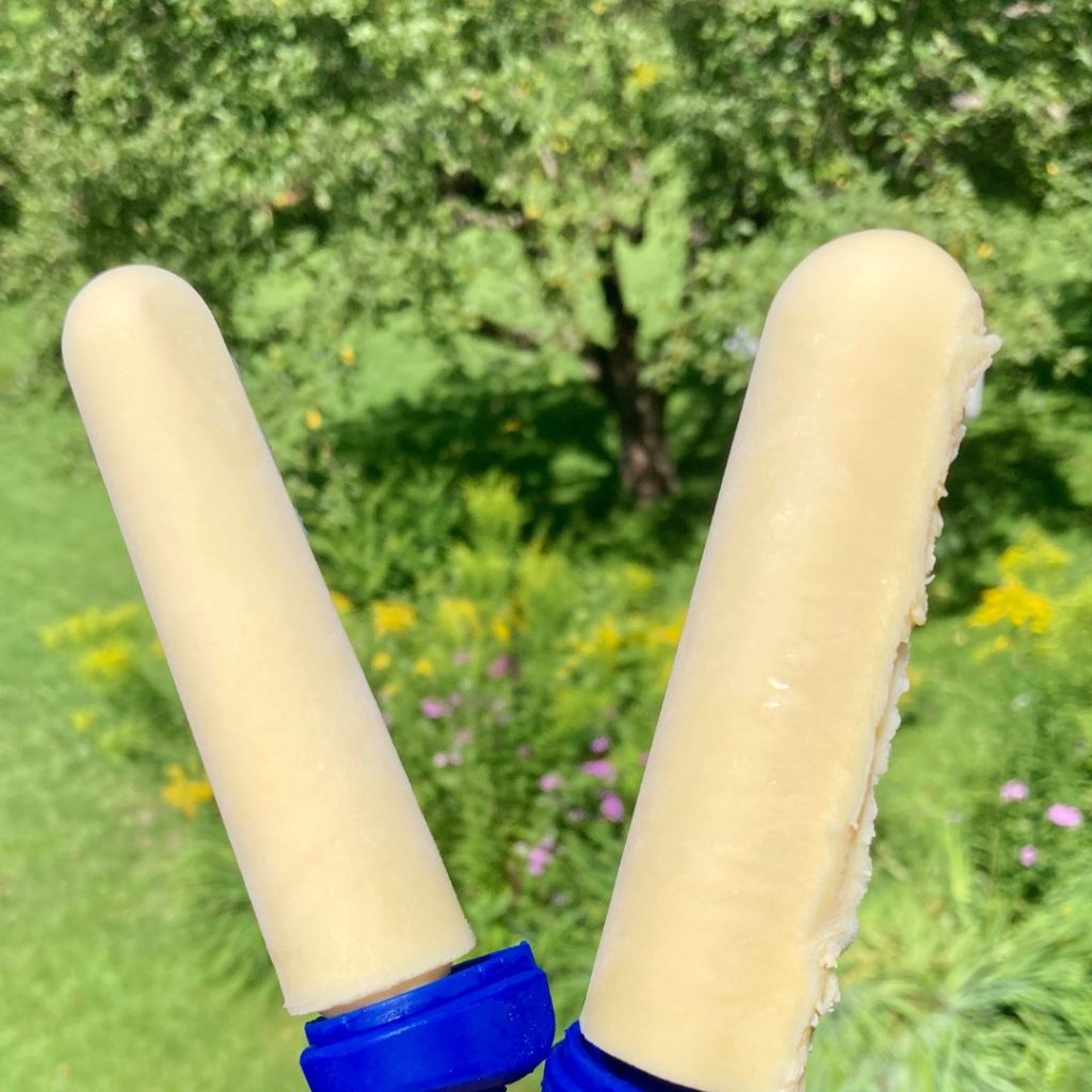 two individual orange creamsicle popsicles outside on a summer day