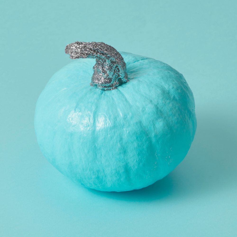 teal painted pumpkin on a teal background